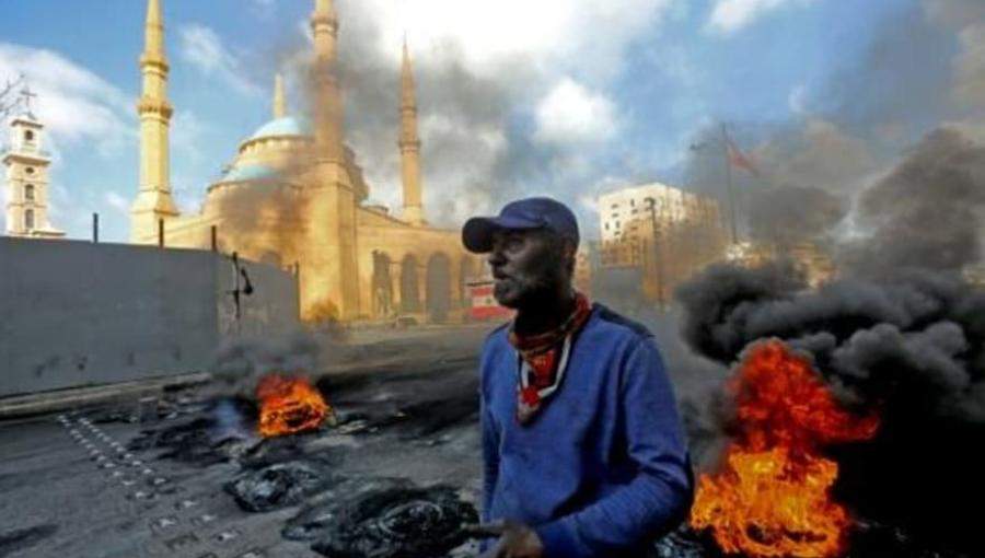 رجل يقف إلى جانب إطارات مشتعلة بجوار مسجد محمد الأمين في ساحة الشهداء في وسط بيروت 8 أذار / فرانس برس2021