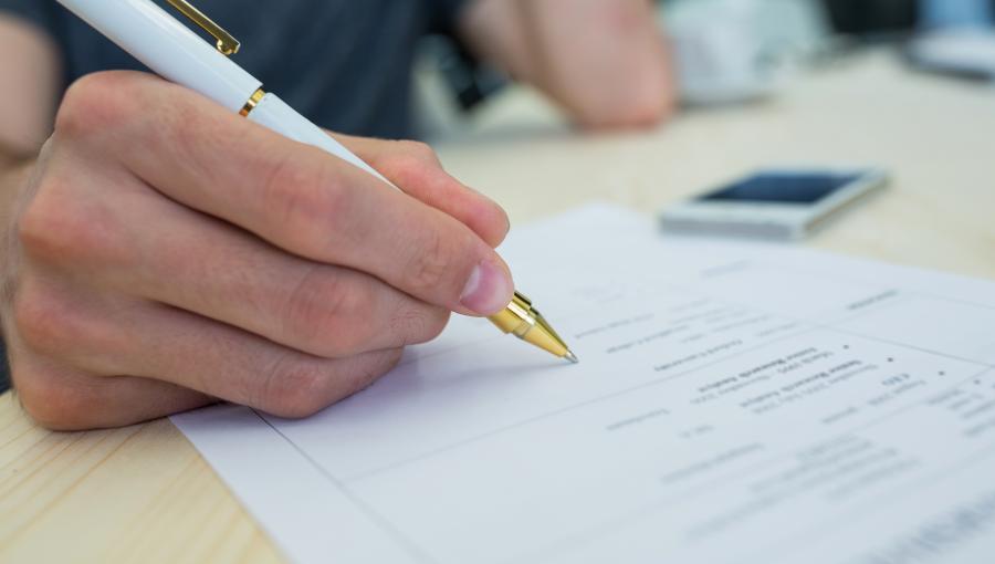 صورة تعبيرية | يد شخص يملأ استمارة | المصدر: freepik