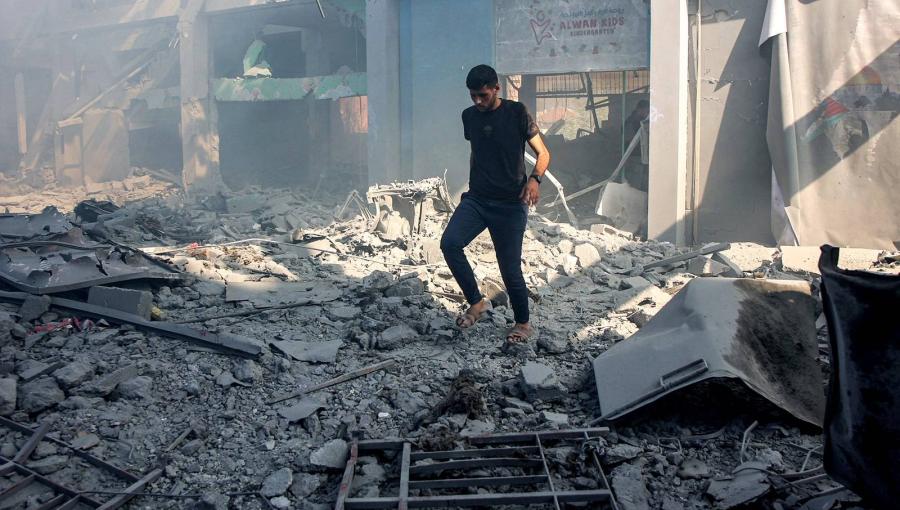 شاب فلسطيني يسير بين أنقاض مبنى تعرض لقصف إسرائيلي في حي الشيخ رضوان بغزة | المصدر: وكالة الأنباء الفرنسية