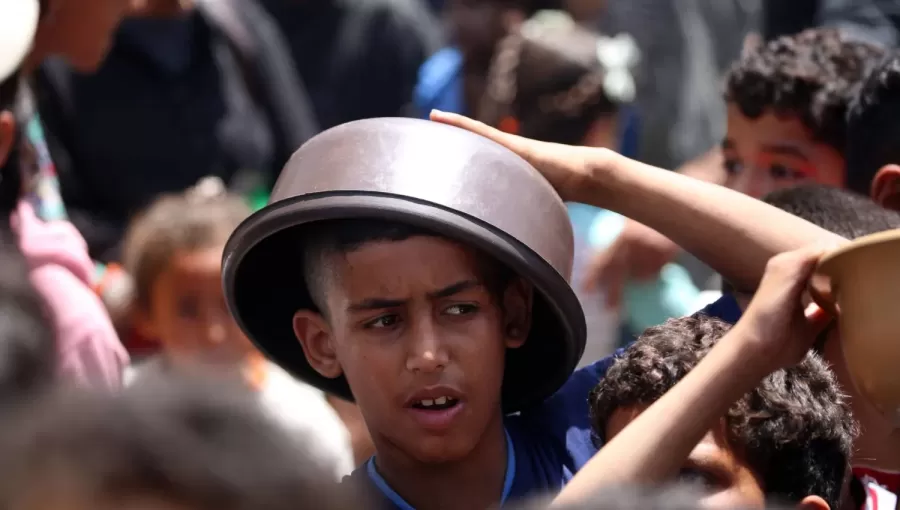 طفل فلسطيني يحمي رأسه من الشمس بوعاء في انتظار الحصول على طعام من تكية في مخيم النصيرات بقطاع غزة طفل فلسطيني يحمي رأسه من الشمس بوعاء في انتظار الحصول على طعام من تكية في مخيم النصيرات بقطاع غزة | المصدر: وكالة الأنباء الفرنسية