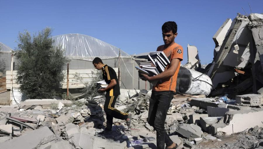 غزيون يحملون كتبا وسط الأنقاض | المصدر: وفا