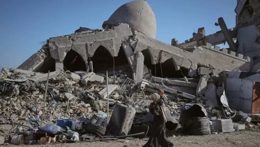 فلسطينية تحمل طفلها وهي تسير أمام مسجد مدمر بمدينة غزة فلسطينية تحمل طفلها وهي تسير أمام مسجد مدمر بمدينة غزة 26/10/2025 | أسوشييتد برس
