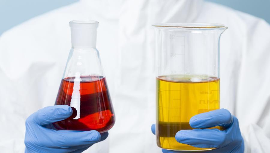 اختصاصي كيمياء يحمل زجاجتين لمواد كيميائية | تعبيرية Freepik