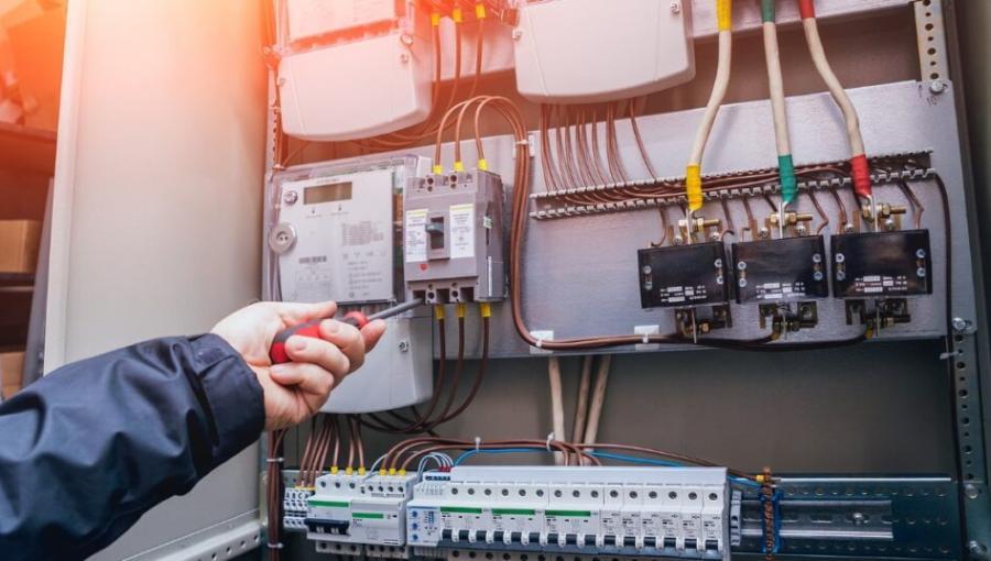 فني كهرباء يستخدم مفكا أثناء العمل داخل لوحة كهربائية | تعبيرية