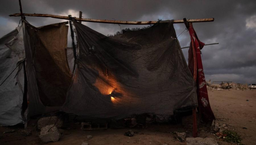 أفراد عائلة فلسطينية نازحة يتجمعون حول نار في خيمتهم في مدينة خانيونس جنوب قطاع غزة | الوكالة الأوروبية للصور الصحفية