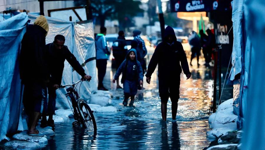 نازحون يمرون عبر برك المياه جراء الأمطار الغزيرة في مدينة غزة 15/12/2025 | وكالة الأنباء الفرنسية
