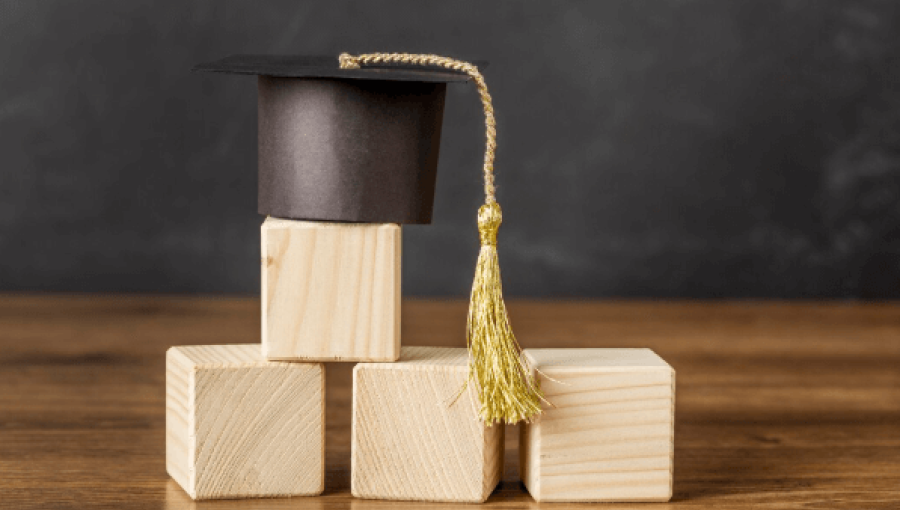 قبعة تخرج فوق مكعبات خشبية | تعبيرية freepik