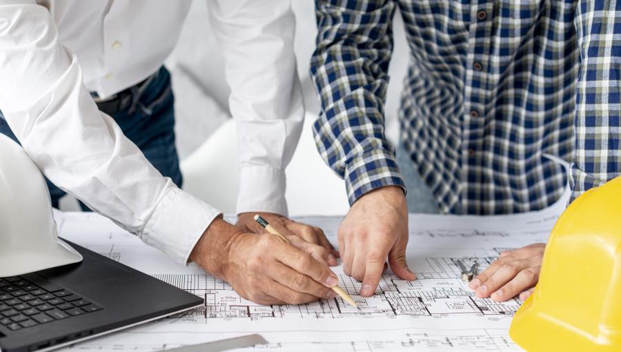 مهندسان يطلعان على مخططات موقع | تعبيرية Freepik