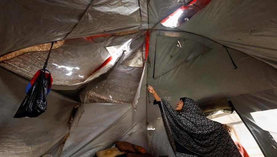 سيدة فلسطينية تعرض سقف خيمتها الممزق في أحد مخيمات النزوح في قطاع غزة | رويترز