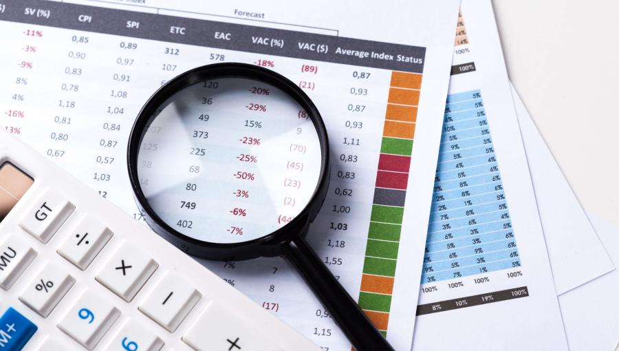 عدسة مكبرة فوق أوراق بجانبها آلة حاسبة | تعبيرية freepik