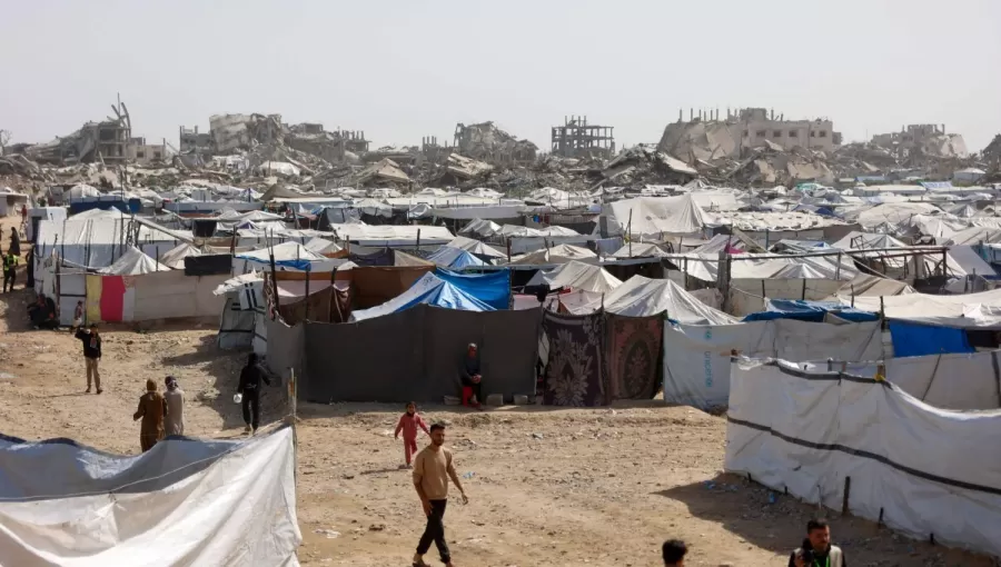 فلسطينيون يسيرون بين مخيمات النازحين المقامة إلى جوار المباني المدمرة في مدينة غزة 16/2/2026 | وكالة الأنباء الفرنسية