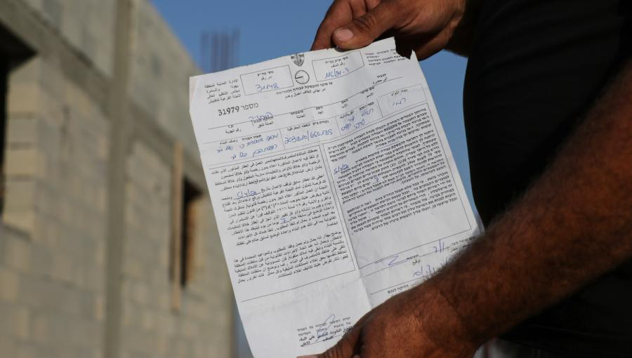 فلسطيني يستعرض إخطارا بهدم منزله تسلمه من قوات الاحتلال في وقت سابق بالضفة الغربية | وفا
