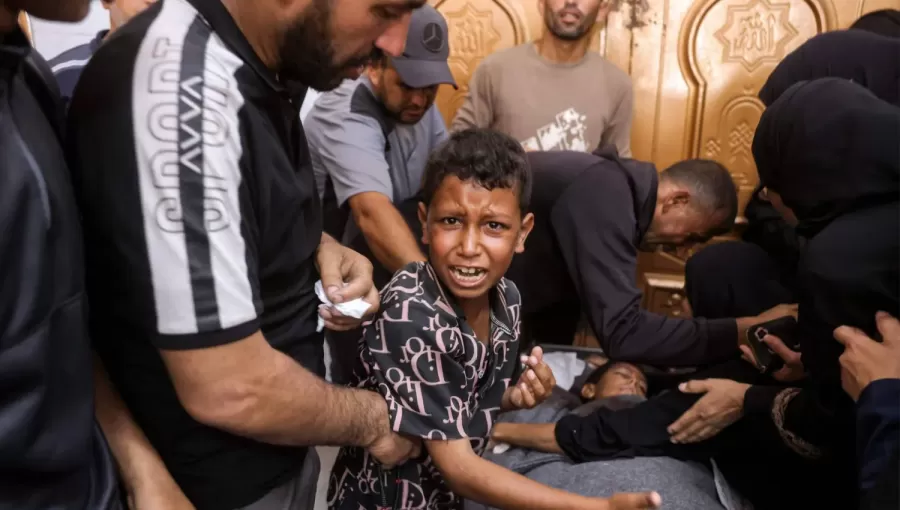 طفل فلسطيني بجوار جثمان شقيقه الذي استشهد بغارة إسرائيلية في خانيونس جنوب غزة 24/6/2026 | وكالة الأنباء الفرنسية