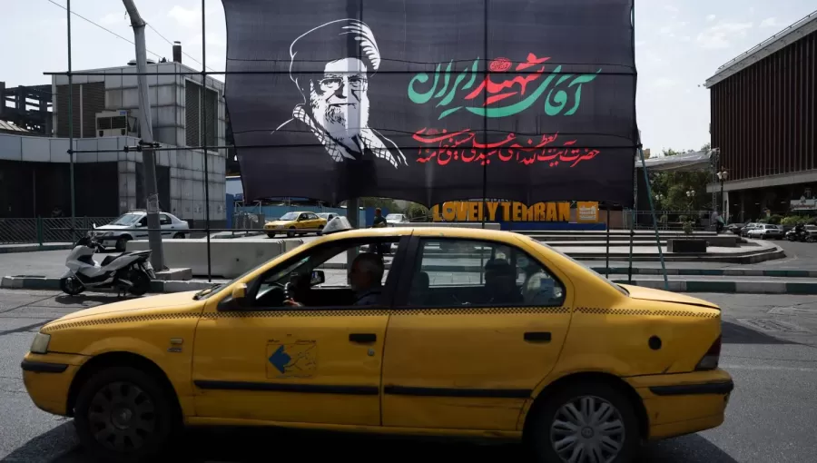 سيارة أجرة تمر أمام لافتة تحمل صورة المرشد الإيراني السابق علي خامنئي قبيل جنازته في طهران | رويترز