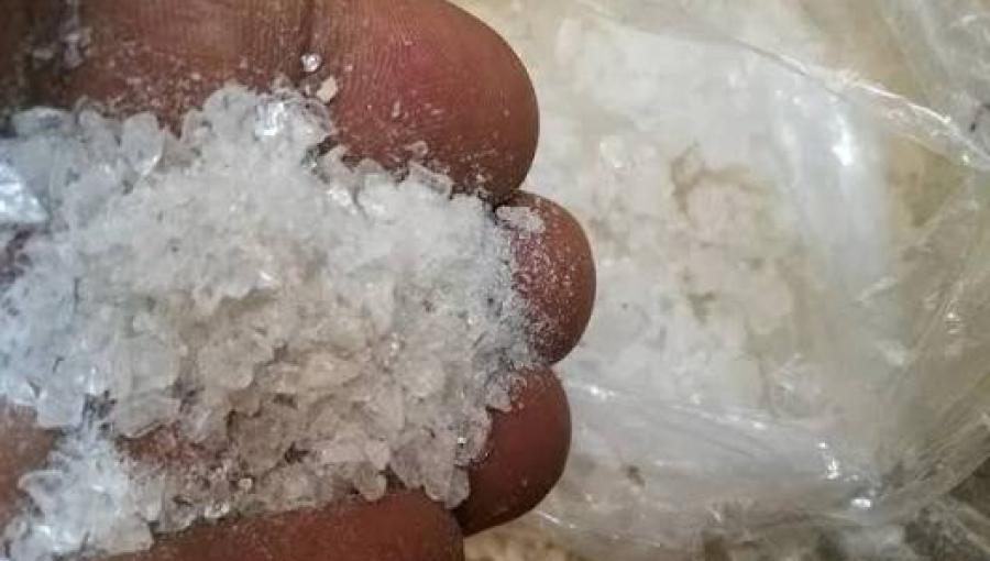 شخص يعرض بيده كمية من مادة الكريستال المخدرة