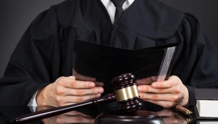 شخص يرتدي روب المحاماة وأمامه مطرقة القضاء