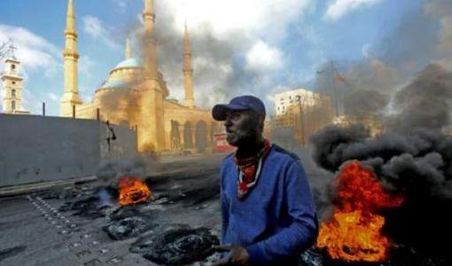 رجل يقف إلى جانب إطارات مشتعلة بجوار مسجد محمد الأمين في ساحة الشهداء في وسط بيروت 8 أذار / فرانس برس2021