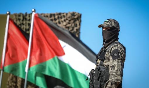أحد رجال المقاومة الفلسطينية مع علم فلسطين أحد رجال المقاومة الفلسطينية مع علم فلسطين