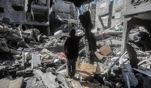 رجل من غزة يقف وسط أنقاض منزله الذي هدمته غارات الاحتلال