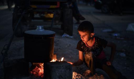 طفل يحاول إشعال الحطب بعد نفاد الوقود بشكل تام