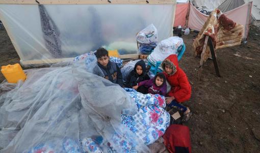 أطفال يجلسون على فراش مغطى بالبلاستيك في مخيم للنازحين برفح، جنوب قطاع غزة 13/12/2023 | المصدر: فرانس برس