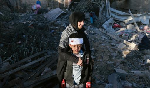 امرأة فلسطينية تحضن صبيا مصابا وهي تتفحص أنقاض مبنى دمره قصف الاحتلال 18/1/2024 | المصدر: وكالة الأنباء الفرنسية