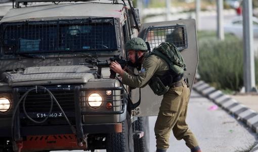 جندي إسرائيلي يوجه سلاحه نحو فلسطينيين خلال اقتحام سابق لإحدى مدن الضفة الغربية | أرشيفية المركز الإعلامي الفلسطيني