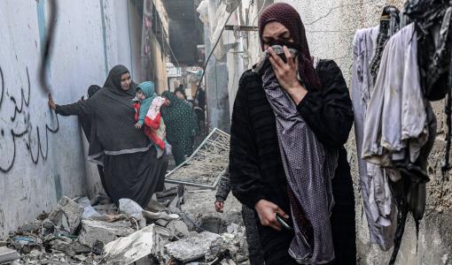 فلسطينيات يعبرن من زقاق في رفح دمرته الغارات الإسرائيلية | المصدر: الوكالة الفرنسية للأنباء