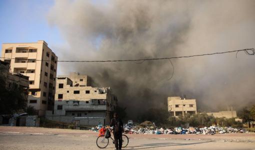 طفل من غزة يقف عند دراجته ويتصاعد مقابله دخان إثر قصف الاحتلال لمنطقة قريبة | المصدر: وكالة الأنباء الفرنسية