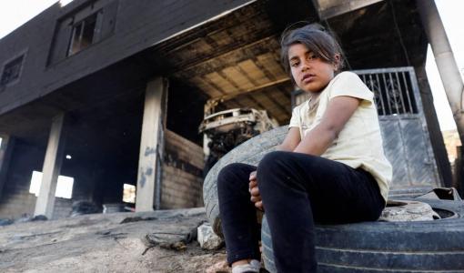 طفلة فلسطينية تجلس أمام منزلها الذي أحرقه مستوطنون في قرية المغير في الضفة الغربية | المصدر: رويترز