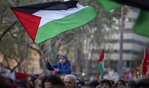 صبي يلوح بالعلم الفلسطيني في برشلونة صبي يلوح بالعلم الفلسطيني في برشلونة وحوله متظاهرون يطالبون بوقف فوري لإطلاق النار في غزة | المصدر: أسوشييتد برس
