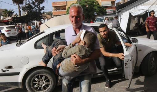 فلسطيني يحمل صبيا مصابا إلى مستشفى شهداء الأقصى في دير البلح | المصدر: وكالة الأنباء الألمانية