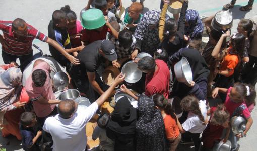 فلسطينيون يتجمعون عند مطبخ خيري في مخيم جباليا للاجئين لملء أوانيهم ببعض الطعام | المصدر: رويترز