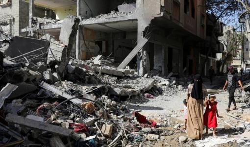 طفلة فلسطينية مع والدتها قرب الدمار التي سببه قصف الاحتلال على مخيم النصيرات وسط قطاع غزة | المصدر: رويترز