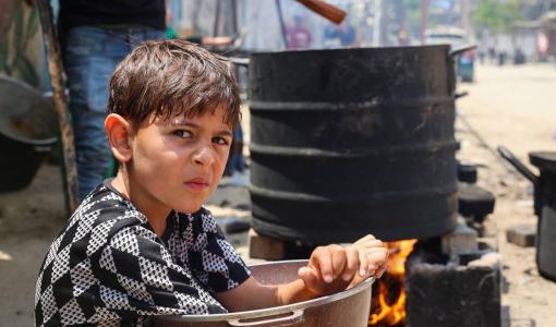 طفل فلسطيني ينتظر نصيبه من الغذاء عند نقطة توزيع طعام جماعية في مخيم البريج للاجئين في قطاع غزة المحاصر 4/6/2024 | المصدر: وكالة الأنباء الفرنسية