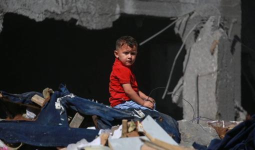 طفل يجلس على أنقاض أحد المنازل المهدمة في مخيم البريج في وسط غزة | المصدر: وكالة الأنباء الفرنسية