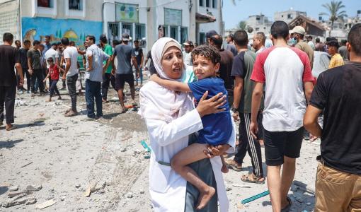 فلسطينيون يتفقدون الأضرار الناجمة بعد غارة إسرائيلية على مدرسة تؤوي نازحين بدير البلح 27/7/2024 | المصدر: وكالة الأنباء الفرنسية