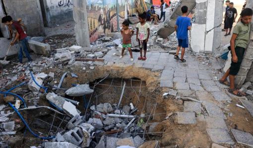 أطفال بالقرب من حفرة أحدثها القصف الإسرائيلي على مدرسة تديرها الأمم المتحدة في النصيرات بوسط قطاع غزة 9/7/2024 | المصدر: وكالة الأنباء الفرنسية