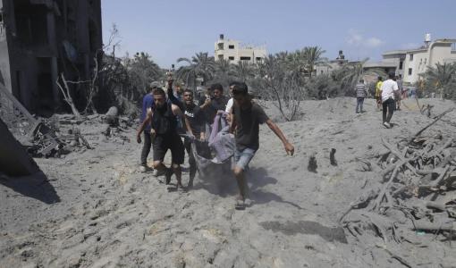 فلسطينيون يحملون جثمان أحد الشهداء من موقع القصف إسرائيلي بمنطقة المواصي في خانيونس 14/7/2024 | المصدر: أسوشييتد برس