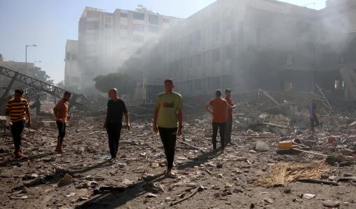 فلسطينيون يسيرون على أنقاض مدرسة تابعة للبطريركية اللاتينية في غزة بعد تعرضها لقصف إسرائيلي 7/7/2024 | المصدر: وكالة الأنباء الفرنسية