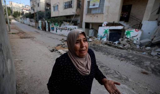 فلسطينية تسير في أحد الشوارع المتضررة خلال مداهمة مخيم نور شمس قرب مدينة طولكرم | المصدر: وكالة الأنباء الفرنسية