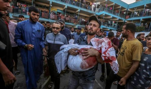 فلسطيني نازح يحمل ابنه الذي استشهد في غارة إسرائيلية على مدرسة الجاعوني التابعة للأونروا وسط قطاع غزة 11/9/2024 | المصدر: وكالة الأنباء الفرنسية