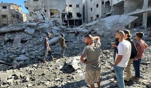 فلسطينيون يقفون أمام الدمار الذي ألحقه الاحتلال ببيت لاهيا شمال قطاع غزة | المصدر: وكالة الأنباء الفرنسية