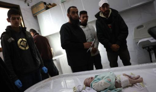 أفراد من عائلة رضيعة استشهدت من البرد ينظرون إلى جثمانها في مستشفى ناصر بخانيونس | المصدر: وكالة الأنباء الفرنسية