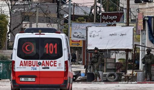 سيارة إسعاف تمر بجانب نقطة تفتيش أقامها الاحتلال خلال مداهمة مخيم نور شمس للاجئين بالقرب من طولكرم | المصدر: وكالة الأنباء الفرنسية