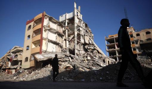 فلسطينيون يسيرون في حي دمره الاحتلال في مخيم النصيرات للاجئين وسط قطاع غزة فلسطينيون يسيرون في حي دمره الاحتلال في مخيم النصيرات للاجئين وسط قطاع غزة | المصدر: وكالة الأنباء الفرنسية