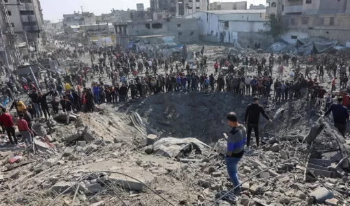 فلسطينيون يتجمعون حول حفرة كبيرة أحدثتها غارة للاحتلال على ورشة حدادة في حي الزيتون بمدينة غزة 13/4/2025 | المصدر: وكالة الأنباء الفرنسية