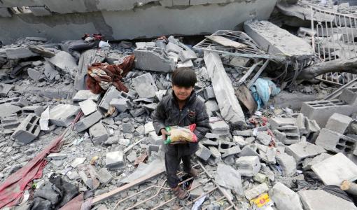 طفل يحمل كيس غذاء في فناء مدرسة دمرتها غارات الاحتلال على حي التفاح بمدينة غزة 4/4/2025 | المصدر: وكالة الأنباء الألمانية