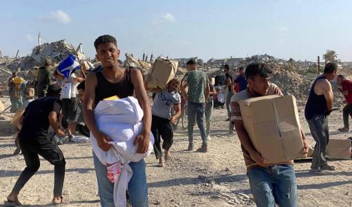 فلسطينيون يحملون مساعدات بالقرب من مركز توزيع مساعدات تديره «مؤسسة إغاثة غزة» المدعومة من واشنطن في رفح جنوب قطاع غزة 27/5/2025 | المصدر: وكالة الأنباء الفرنسية