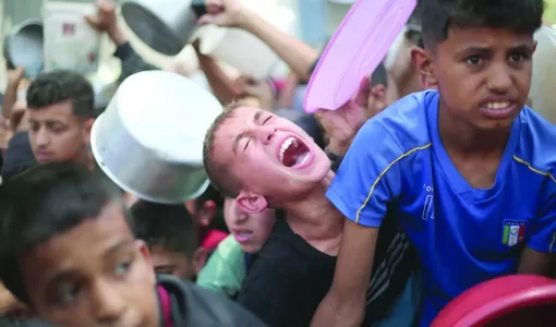 أطفال فلسطينيون ينتظرون الطعام عند نقطة توزيع في النصيرات وسط قطاع غزة 11/6/2025 | المصدر: وكالة الأنباء الفرنسية